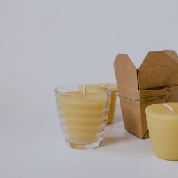 A variety of beeswax candles in glass, cardboard and bare on a white background