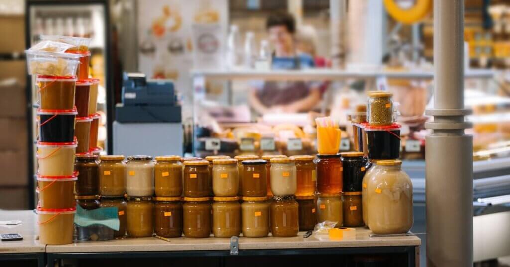 A counter full of honey jars with orange price stickers. The honey comes in different sizes, colors, and textures.