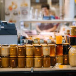 A counter full of honey jars with orange price stickers. The honey comes in different sizes, colors, and textures.